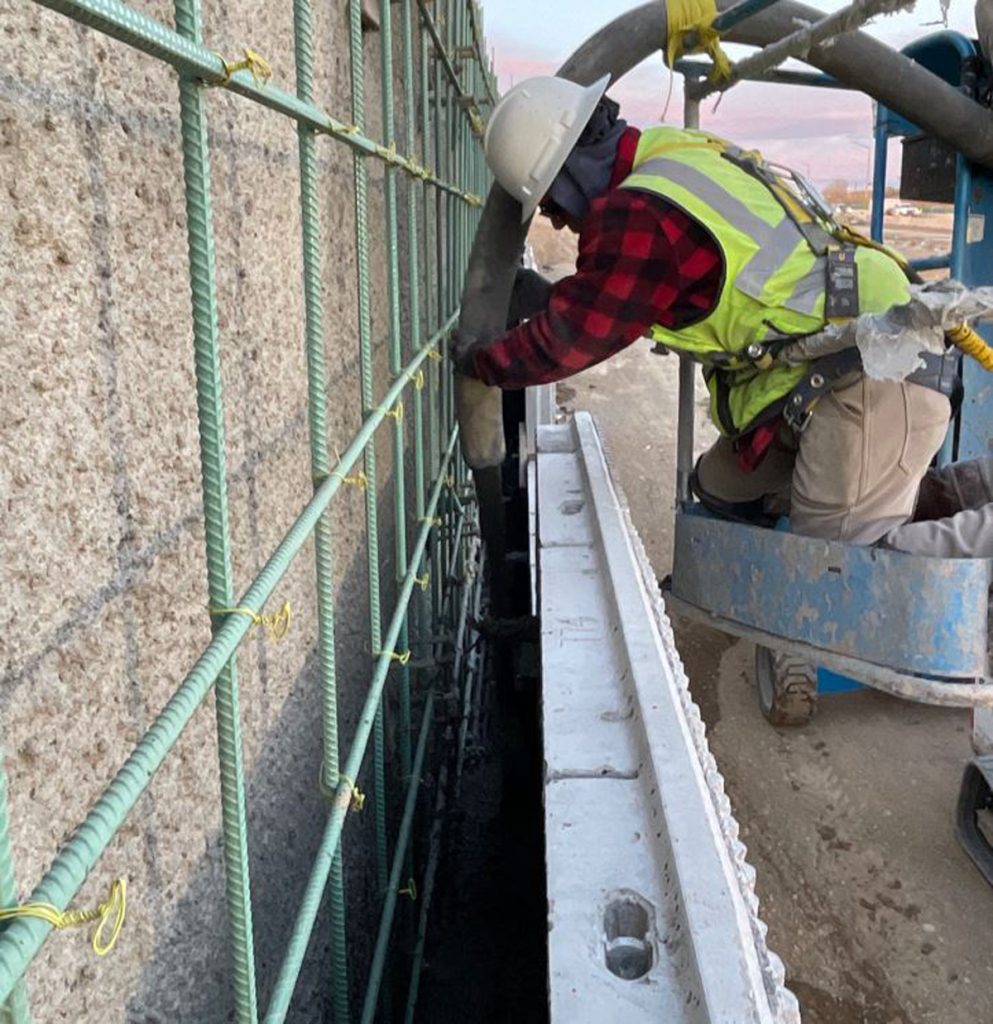 A person working on a precast panel retaining wall in Denver, Colorado.